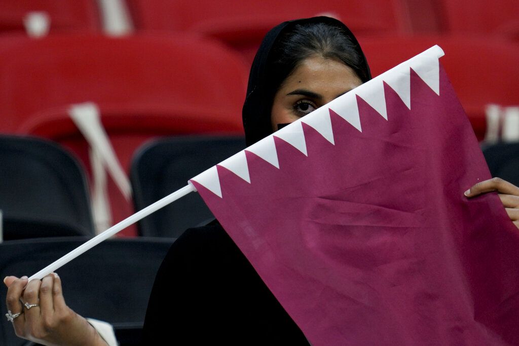 A Qatari fan holds the Qatar national flag prior to the World Cup, group A soccer match between Qatar and Ecuador at the Al Bayt Stadium, in Al Khor, Sunday, Nov. 20, 2022.