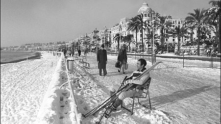 A man takes off his skis to rest at the Promenade des Anglais after  rare heavy snowfall in Nice, France. January 8, 1985