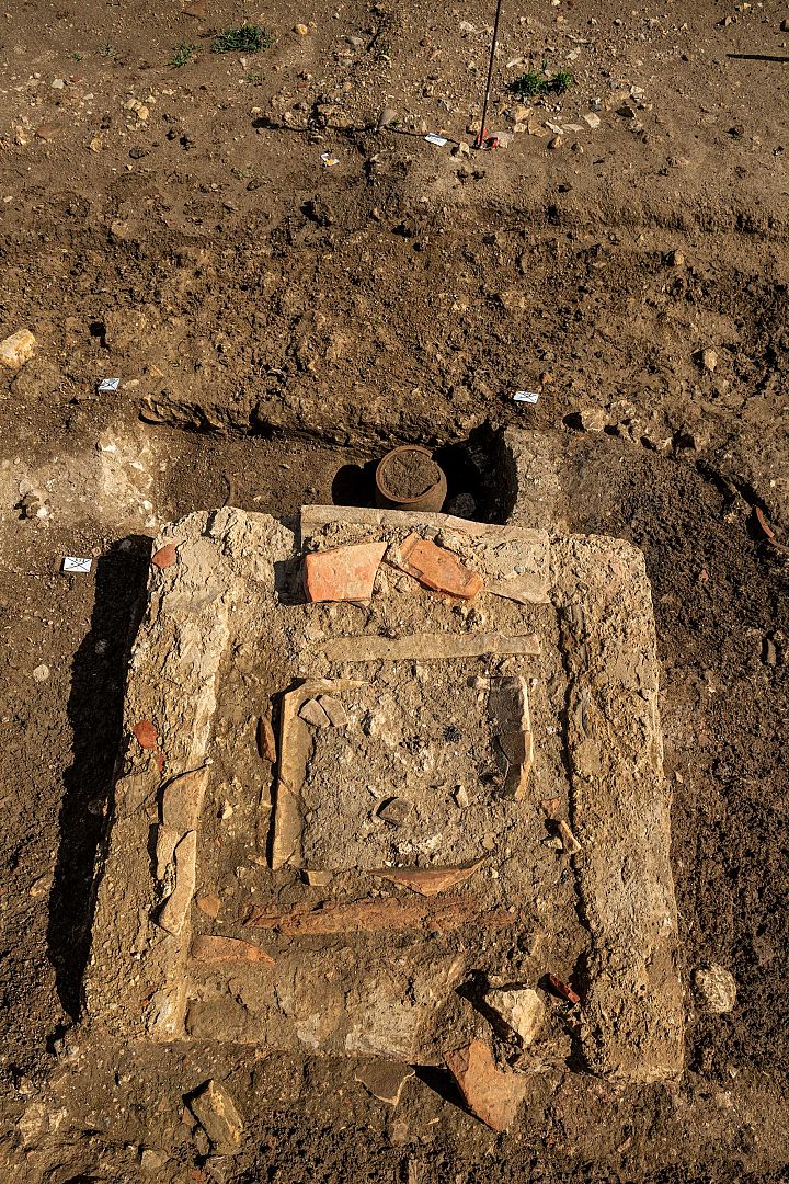 Tombes à crémation en cours de fouille et enclos funéraire avec petit monument, installés le long d’un chemin de desserte