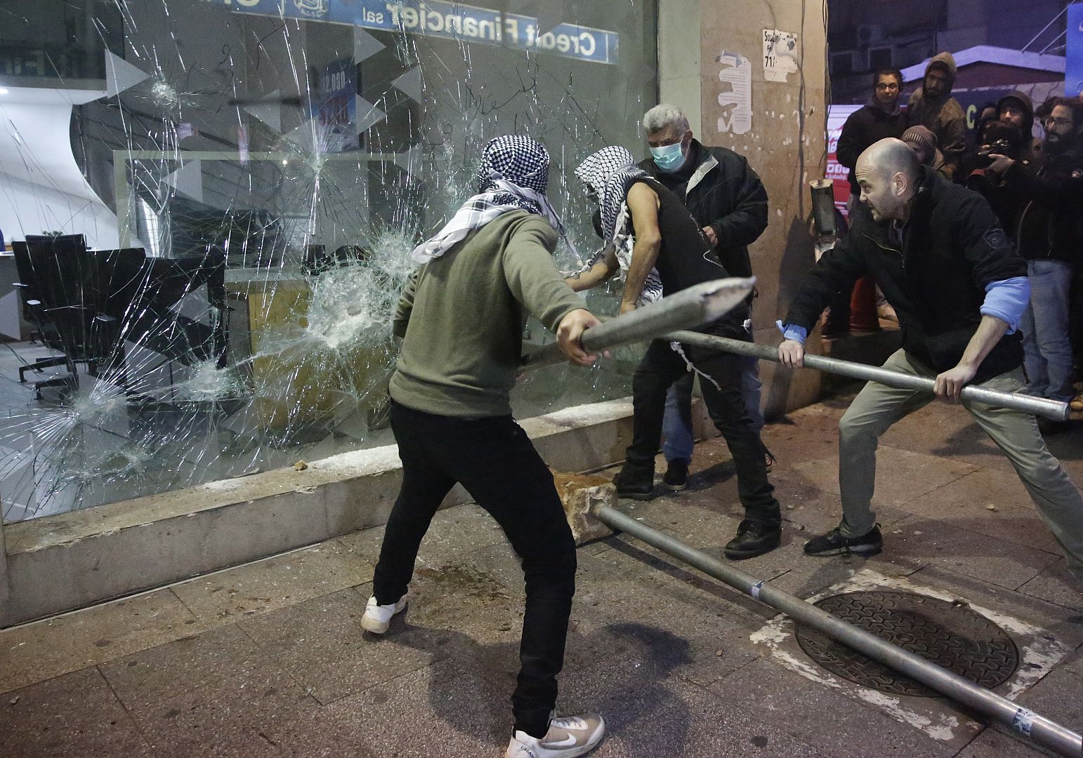 Anti-government protesters smash a bank widow, during ongoing protests against the Lebanese central bank's governor and against the deepening financial crisis. 14 Jan. 2020.