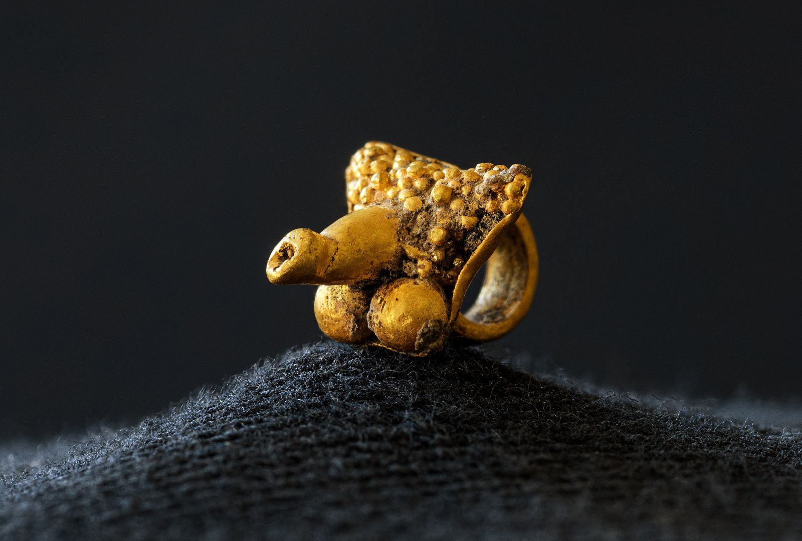 Pendentif ithyphallique en or trouvé parmi les résidus collecté de bûcher déposés dans une tombe à crémation