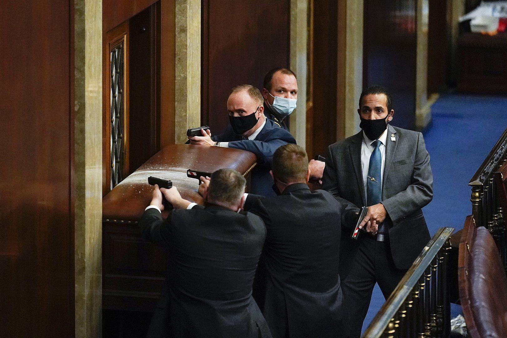 La policía del Capitolio de EE. UU. Con armas desenfundadas cerca de una puerta con barricadas mientras los manifestantes intentan irrumpir en la Cámara de la Cámara en el Capitolio de EE. UU., Washington, EE.  6 de enero de 2021