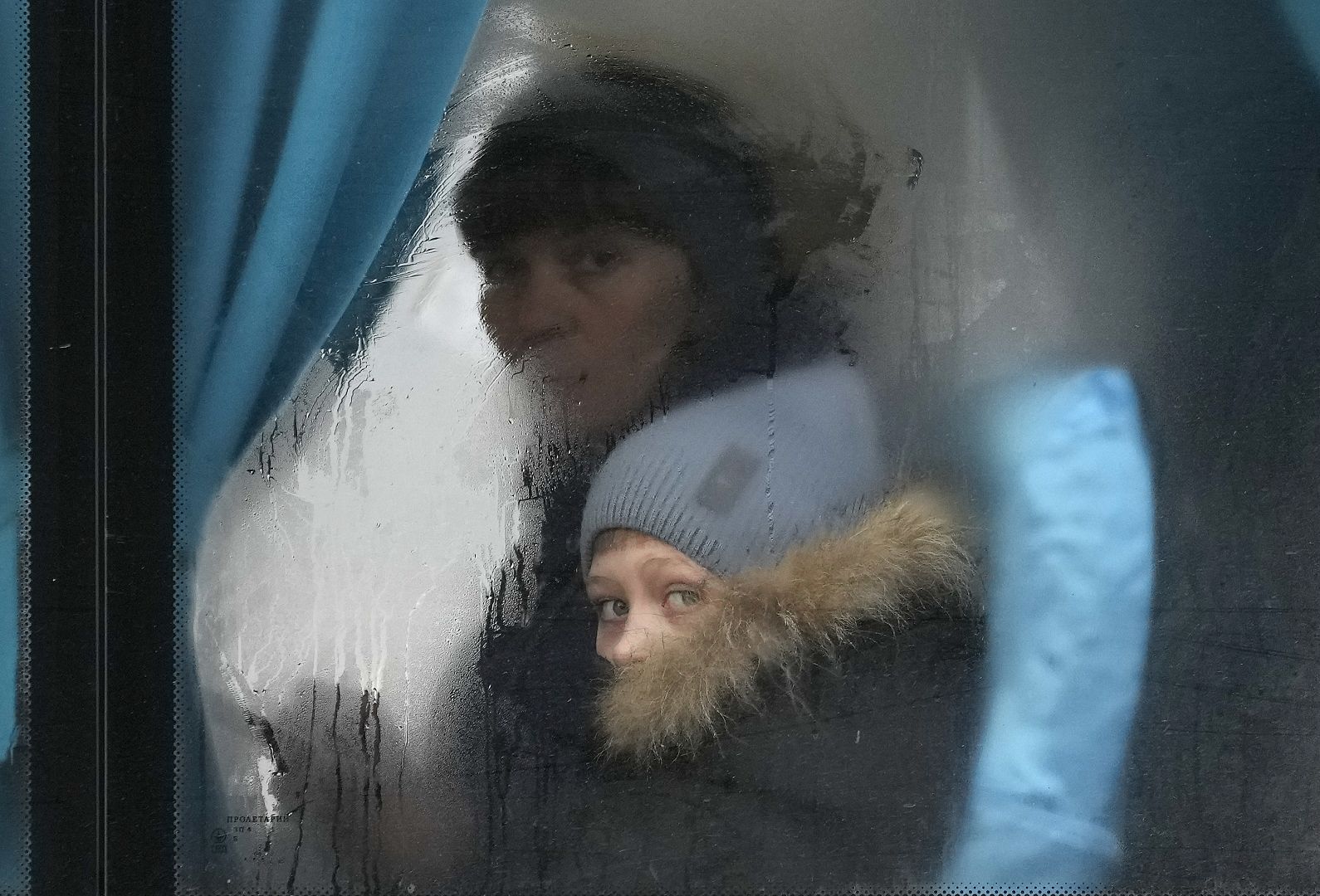 A woman and child peer out of the window of a bus as they leave Sievierodonetsk, the Luhansk region, eastern Ukraine. February 24, 2022