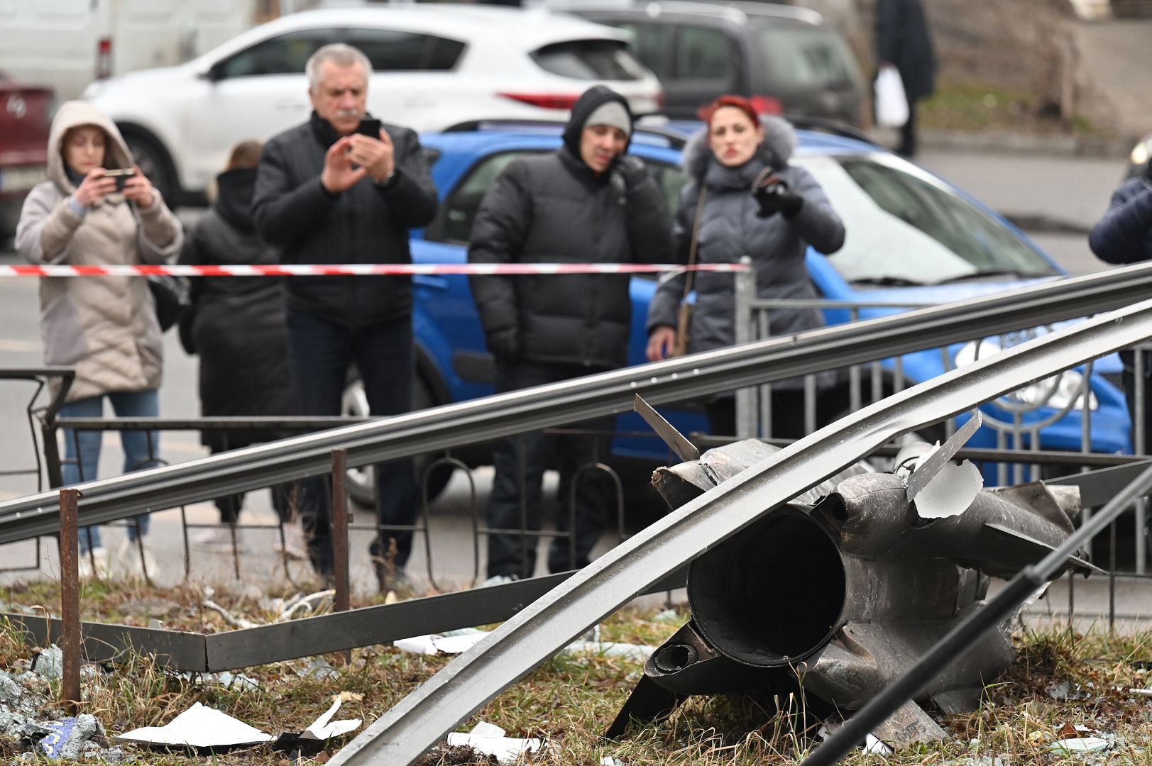 People stand behind the cordoned off area around the remains of a shell in Kyiv, Ukraine. February 24, 2022