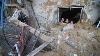 أطفال فلسطينيون ينظرون إلى مبنى عائلة زنون الذي دمرته الغارات الجوية الإسرائيلية في رفح بقطاع غزة