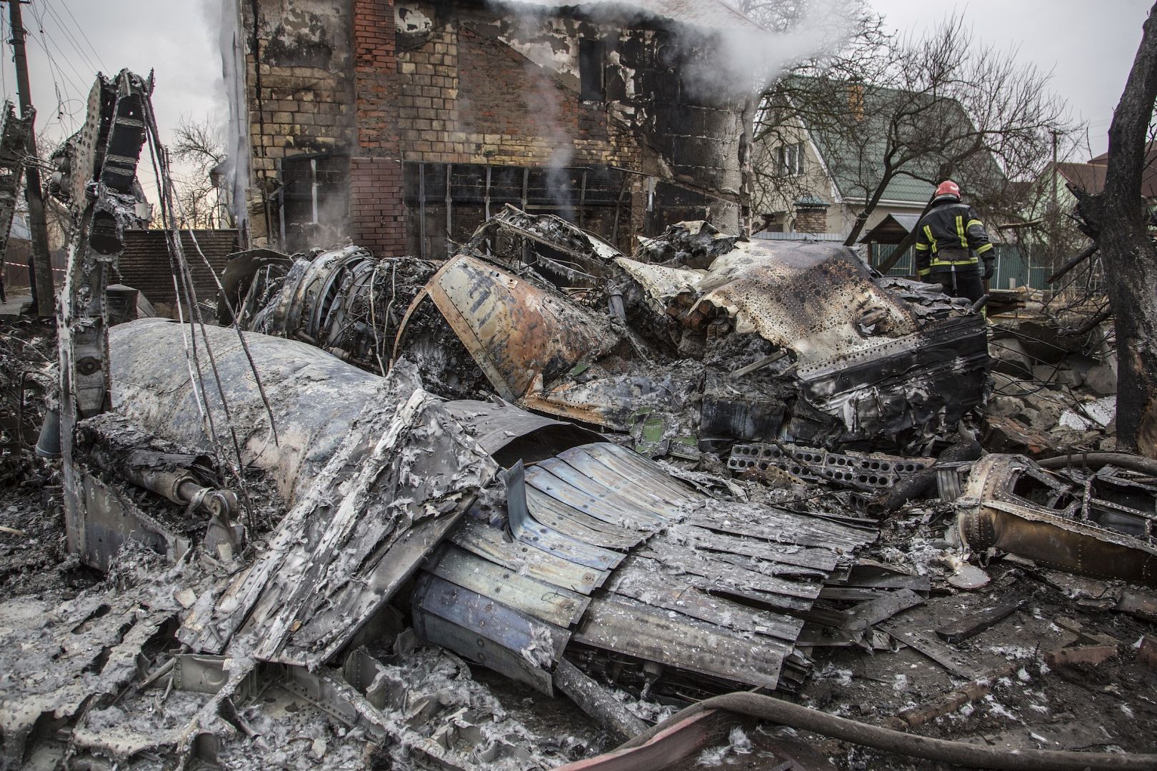 A Ukrainian firefighter walks between at fragments of a downed aircraft seen in in Kyiv, Ukraine. February 25, 2022.