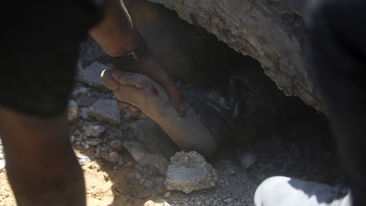محاولة انتشال جثة صبي من تحت الركام بعد غارة إسرائيلية على خان يونس