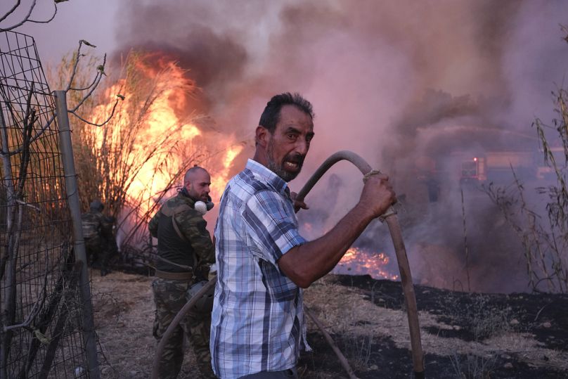 Volunteers try to extinguish the fire in northern Athens, Monday, Aug. 12, 2024, as hundreds of firefighters tackle a major wildfire raging out of control.