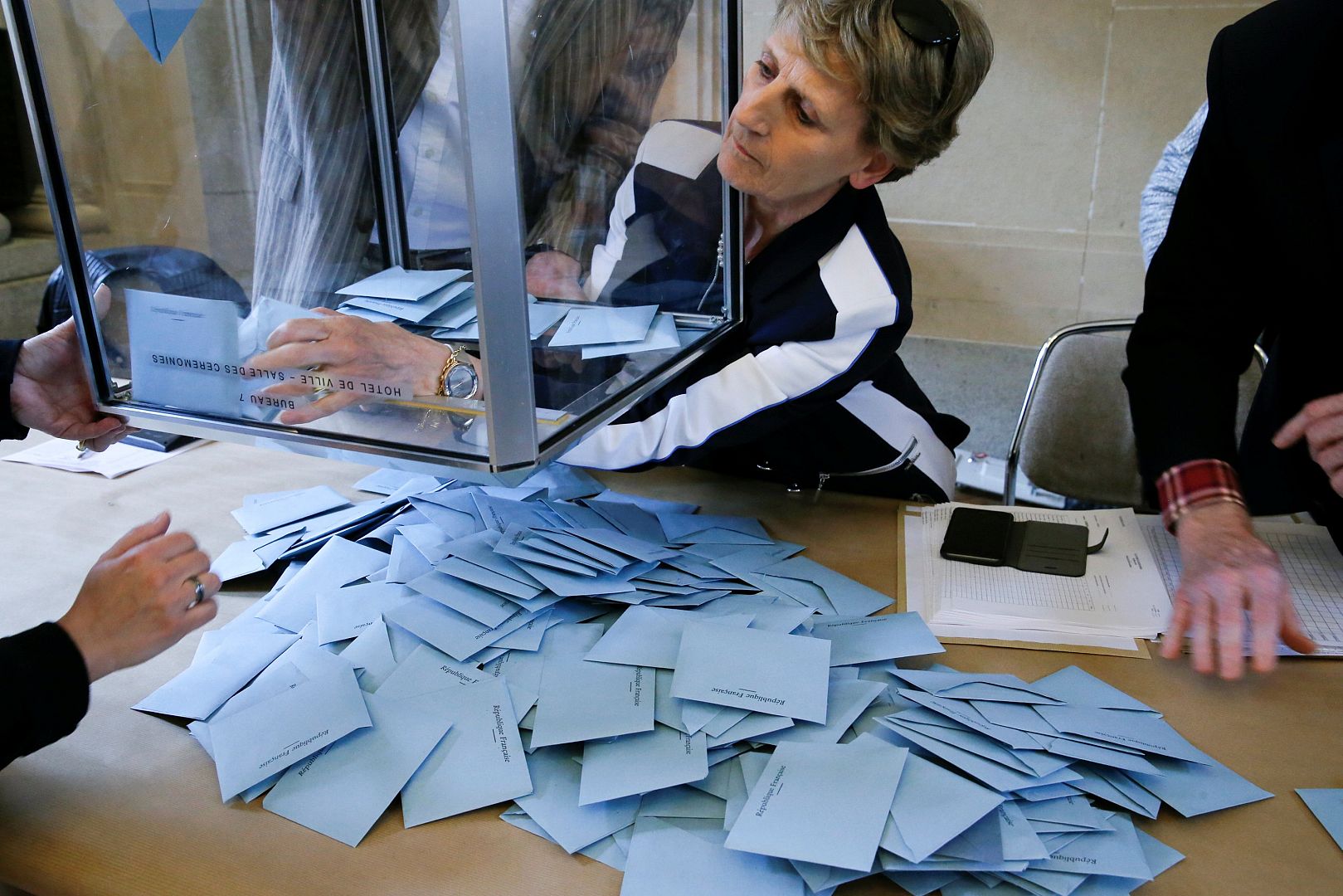 Election officials empty a ballot box as vote counting starts