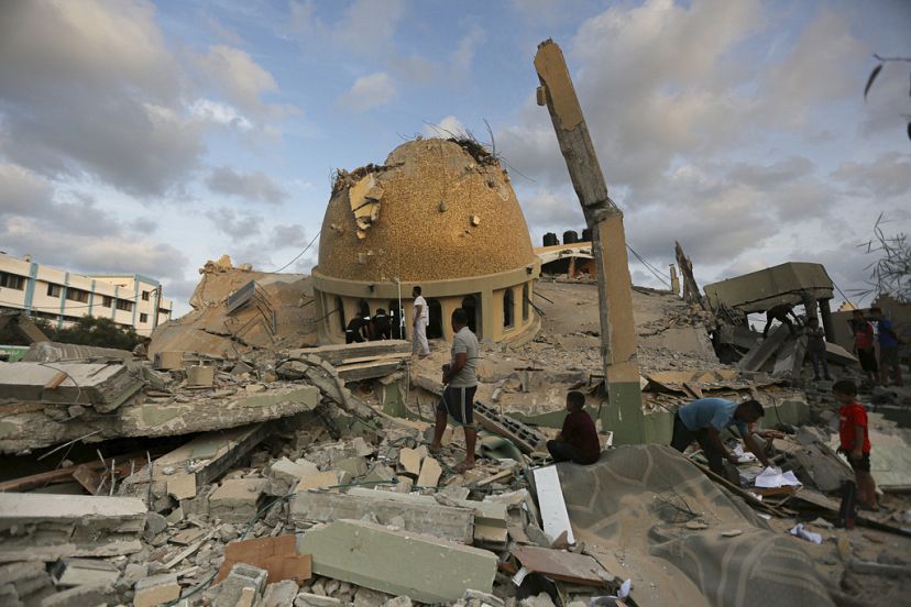 Personas frente a mezquita destruida por un ataque aéreo israelí en Jan Yunis, Franja de Gaza, domingo 8 de octubre de 2023