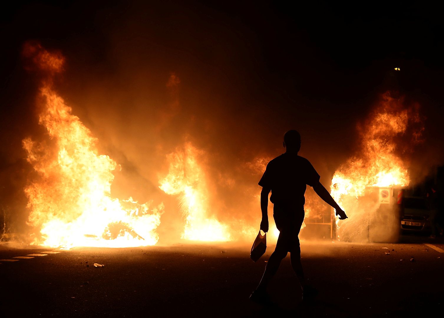 Una persona camina por delante de un incendio en Barcelona, el 16 de octubre de 2019.