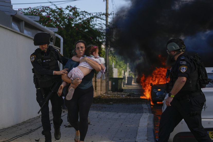 Oficiales de policía evacuan a una mujer y a un niño de un lugar alcanzado por un cohete disparado desde la Franja de Gaza, en Ashkelon, al sur de Israel, sábado 7 de octubre 