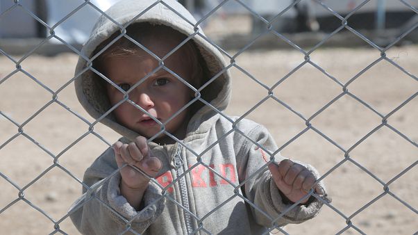 A child looks through a chain linked fence at al-Hol displacement camp A child looks through a chain linked fence at al-Hol displacement camp