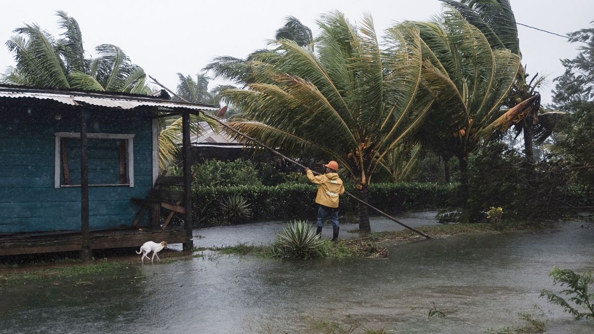 A man fixes the roof of a home surrounded by floodwaters brought on by Hurricane Eta in Wawa, Nicaragua.