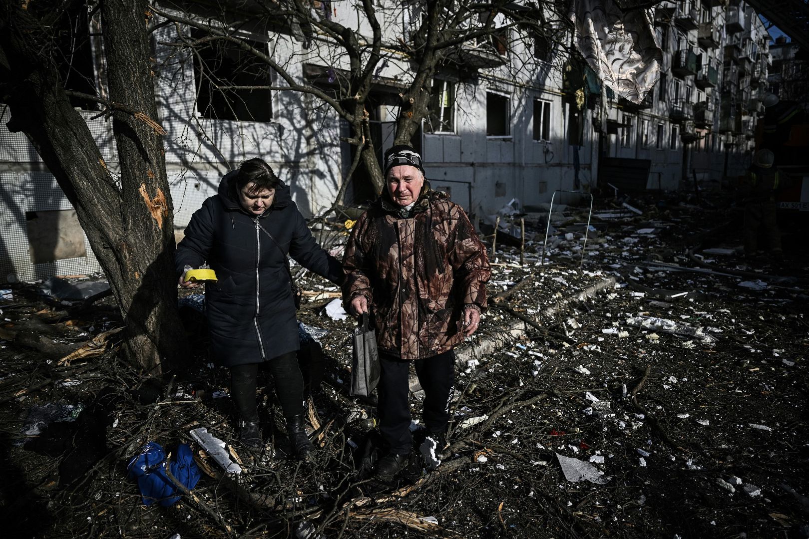 People walk past the body of a relative outside a destroyed building after bombings on the eastern Ukraine town of Chuguiv, Ukraine. February 24, 2022