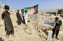 Afghan boys play with flags at a cemetery near Kabul. One group holds the former government’s flag, while the boy on the right shows what seems to be a Taliban flag.