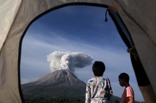 Indonesian children watch Mount Sinabung erupting in Karo, North Sumatra, Indonesia. March 11, 2021