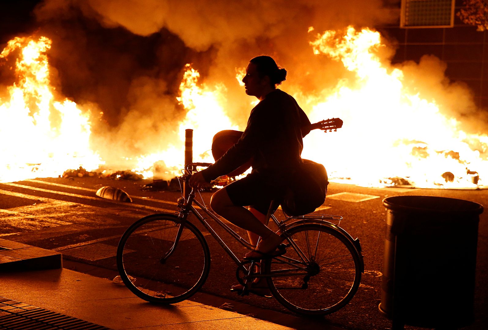 Un hombre pasa en bicicleta junto a un incendio en Barcelona, España, el 15 de octubre de 2019.
