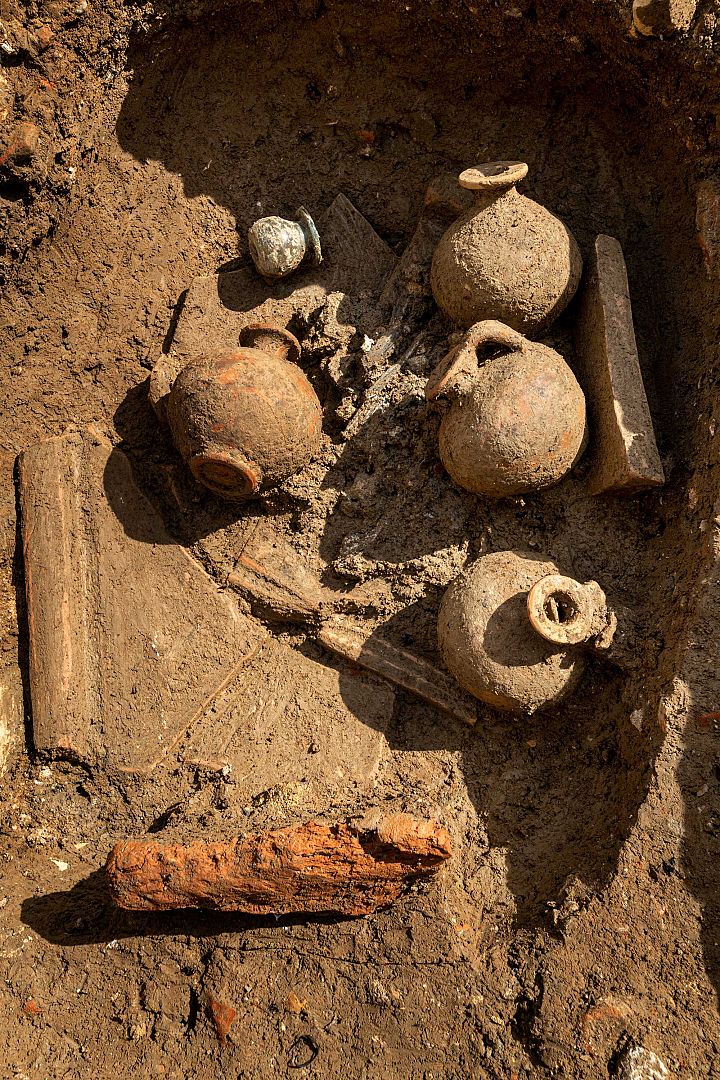 Tombe à crémation constituée d’un amas d’ossements humains brûlés surmonté de cruches en céramique et d’un petit balsamaire (vase à parfum) en verre.