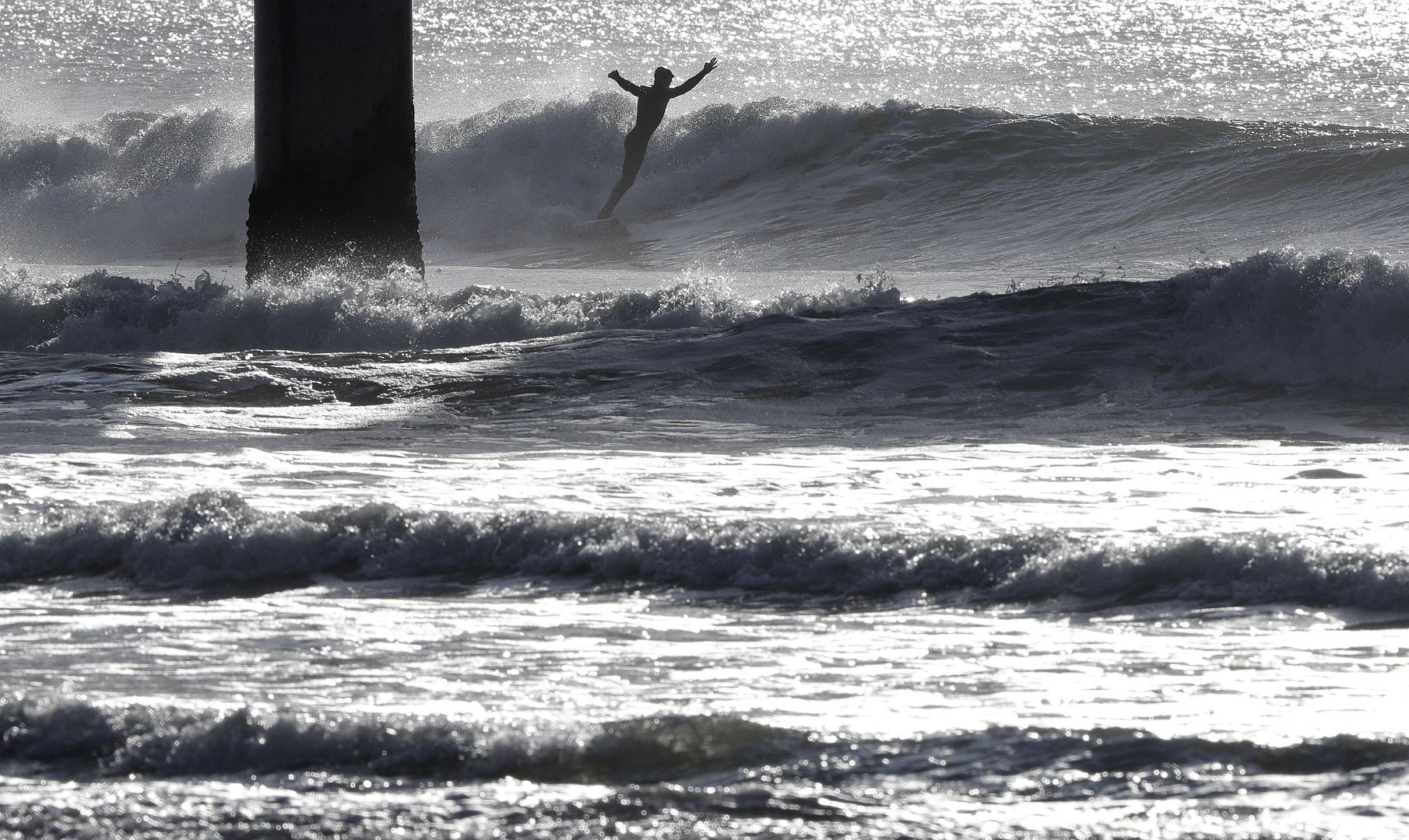 A surfer rides a winter wave at New Brighton Beach in Christchurch, New Zealand. 2 July 2020
