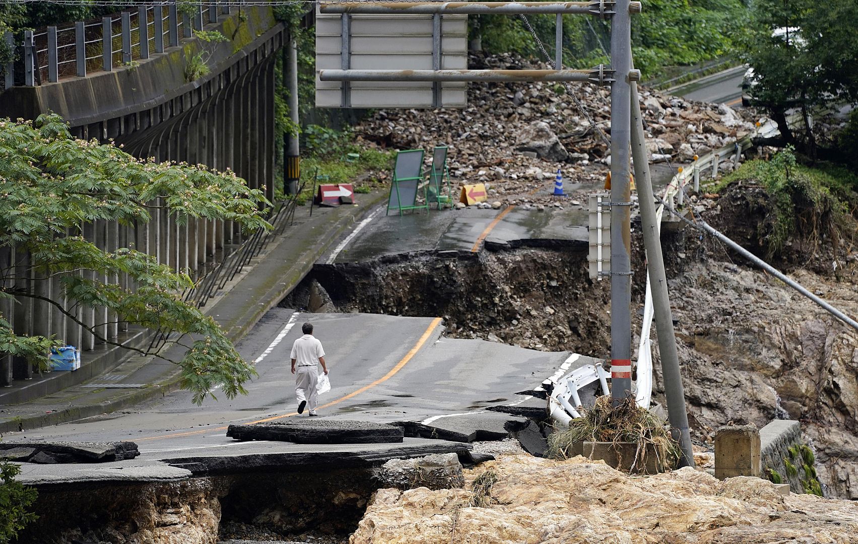 A man walks on heavily damaged road following a heavy rain in Kumamura, Kumamoto prefecture, southern Japan. 6 July 2020