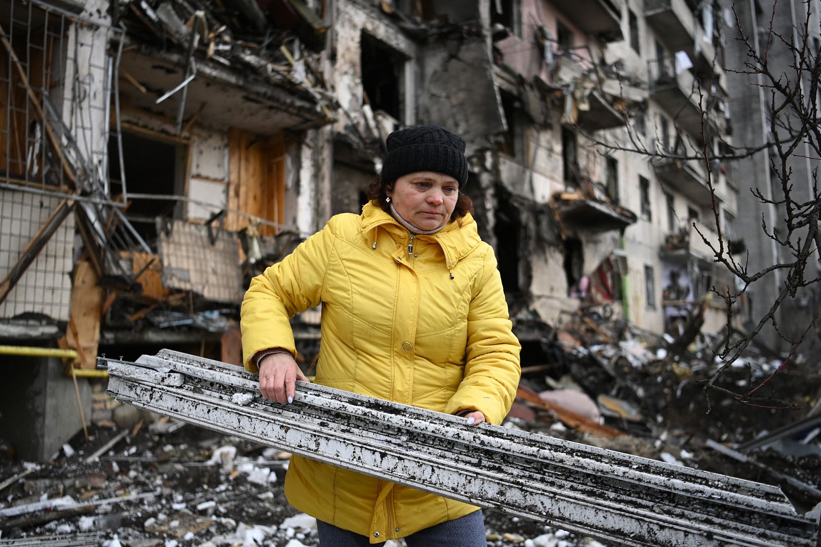 A woman clears debris at a damaged residential building at Koshytsa Street, a suburb of the Ukrainian capital Kyiv, where a military shell allegedly hit. February 25, 2022