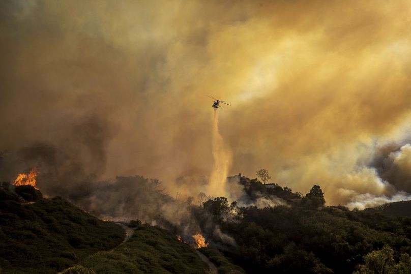 Ein Hubschrauber wirft am Dienstag, 7. Januar 2025, im Stadtteil Pacific Palisades von Los Angeles Wasser auf das sich ausbreitende Palisades-Feuer.
