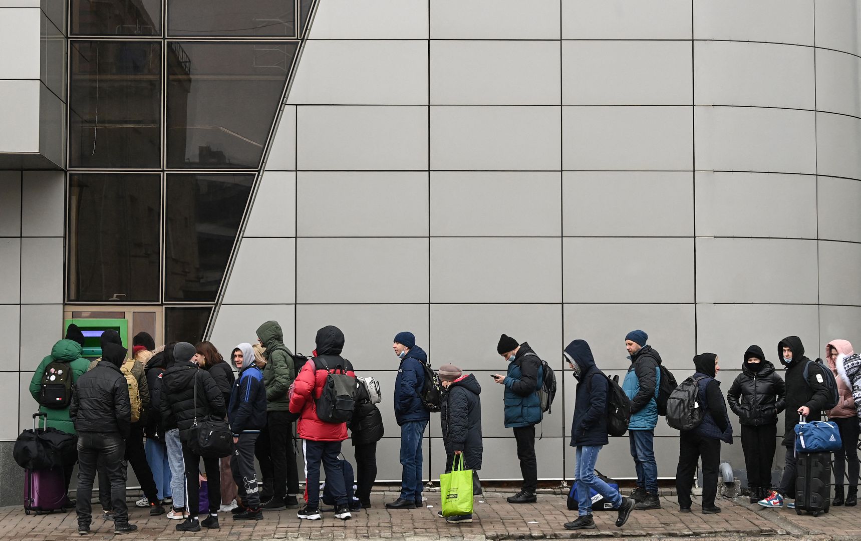 People line up to withdraw money at a cash dispenser in Kyiv, Ukraine, in the morning of February 24, 2022 