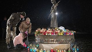 Menschen legen Blumen nieder am Denkmal für die Opfer des Holodomor, der großen Hungersnot, nieder, bei der in den 1930er Jahren Millionen Menschen starben