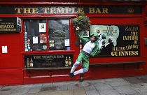 Egy férfi Szent Patrik napi öltözékben Dublin legendás pubja, a Temple Bar előtt