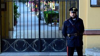 Italian Carabinieri police officer patrols outside the cemetery in Corlene