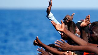 Migrants gesture as before they are rescued by SOS Mediterranee organisatio