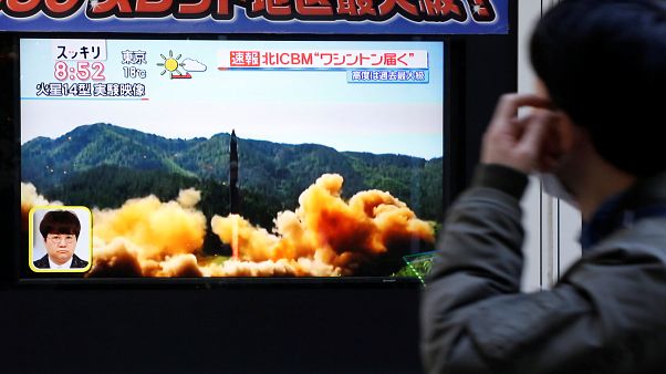 Egy férfi nézi a rakétakilövésről szóló hírt a tévében Tokióban Egy férfi nézi a rakétakilövésről szóló hírt a tévében Tokióban