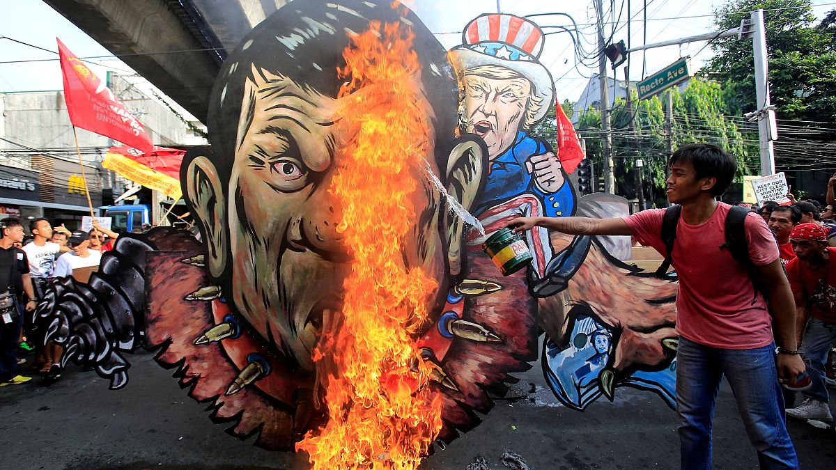 An activist pours gasoline as an effigy of President Rodrigo Duterte