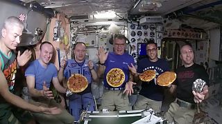 Astronauts aboard the International Space Station show off their pizzas.