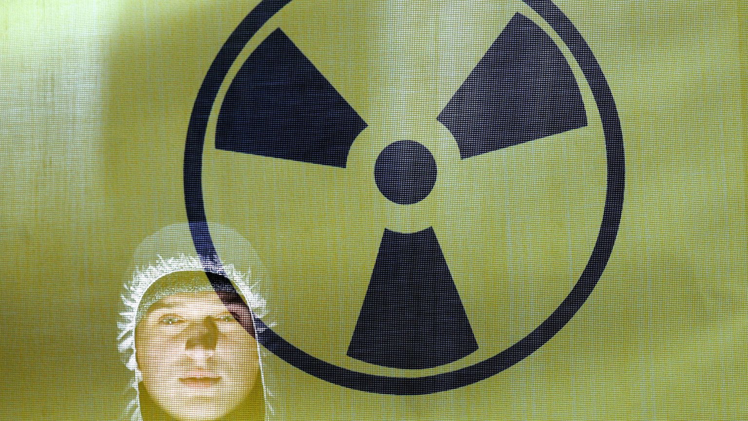 A Greenpeace activist hammers into the ground warning signs regarding the t