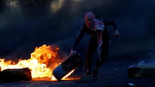 Palestinian moves a tire during clashes with Israeli troops at a protest