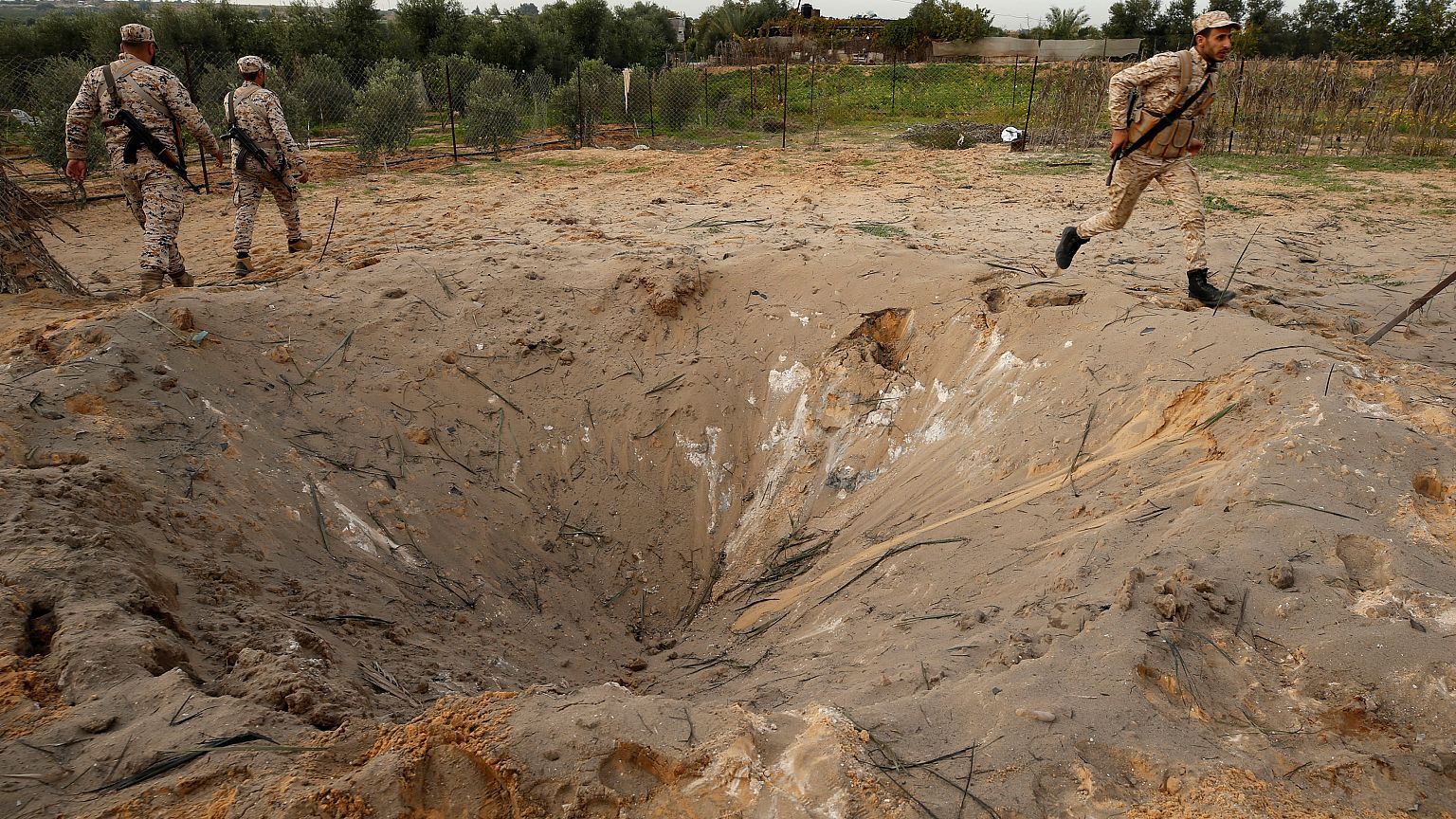 مقاتلون من حركة حماس يفحصون موقع غارة إسرائيلية شمال قطاع غزة