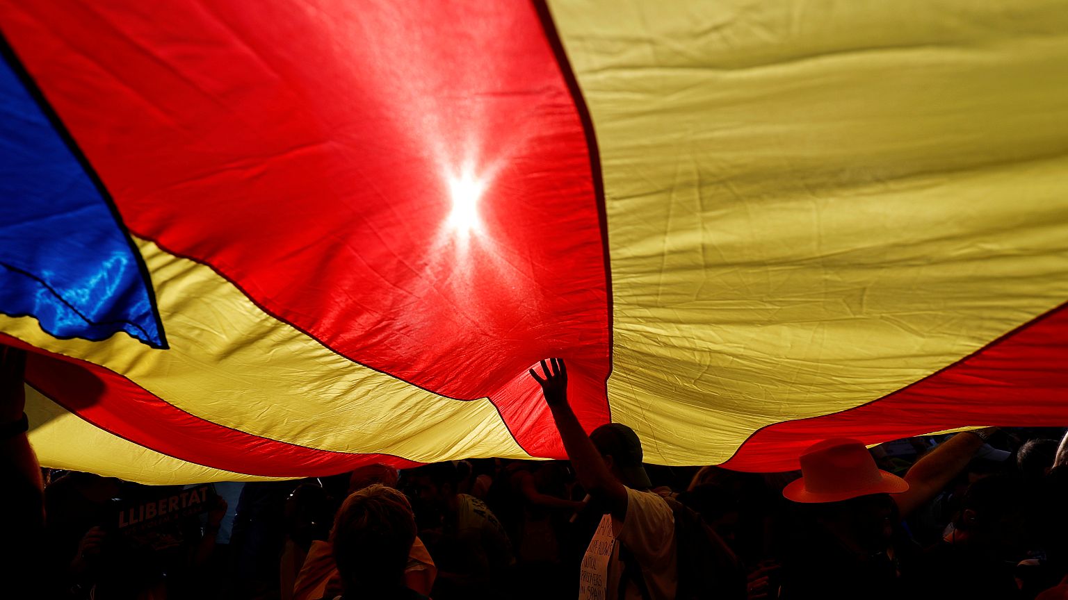 People stand under a giant separatist Catalonian flag during a demonstratio