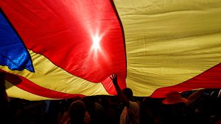 People stand under a giant separatist Catalonian flag during a demonstratio