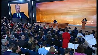 La periodista Ksenia Sobchak, de pie con un vestido rojo, pregunta a Putin