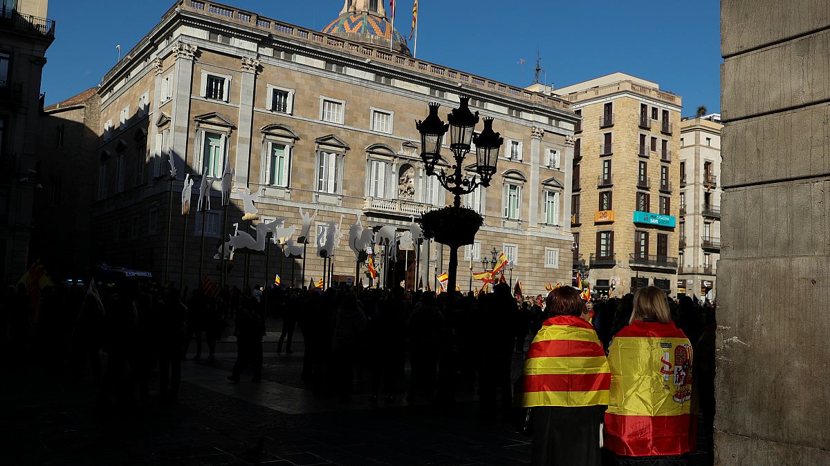 Woman wear Spanish and Catalan flags as they gather at Sant Jaume square
