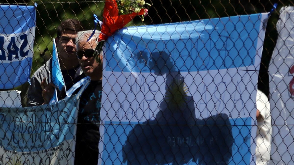 People stand next to a bouquet of flowers in support of missing submarine
