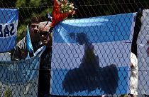 People stand next to a bouquet of flowers in support of missing submarine