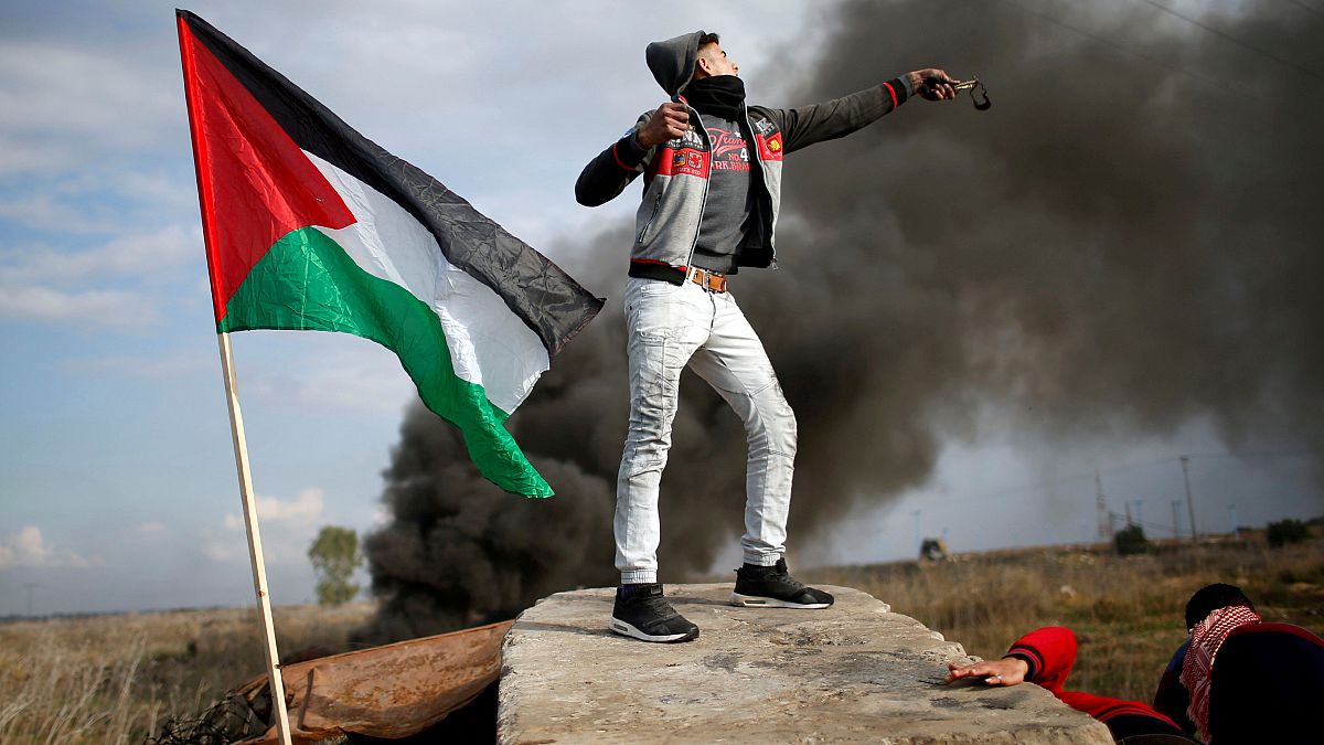 Egy palesztin tüntető csúzlival repít követ az izraeli katonák felé Gázában