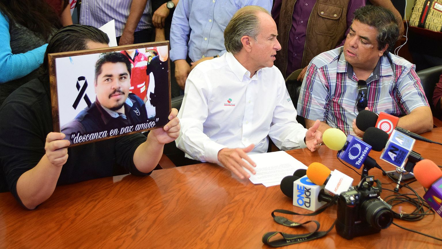 A journalist (L) holds a framed picture of slain photojournalist Daniel Esq
