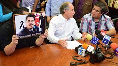 A journalist (L) holds a framed picture of slain photojournalist Daniel Esq