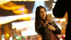 A woman takes a selfie on a street with Christmas decoration in Tbilisi, Ge
