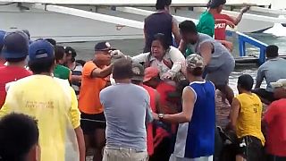 Varias personas ayudan a desembarcar a una superviviente del ferry