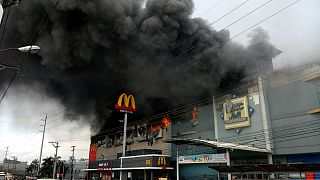Smoke billows from a shopping mall on fire in Davao City